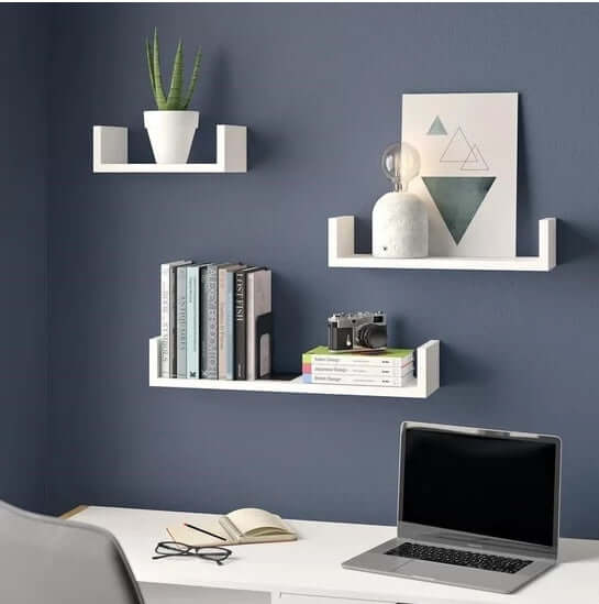 White wood wall-mounted shelf set displayed in a modern home office with books, decorative items, and a laptop.