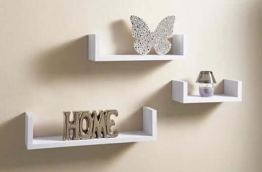 White wood wall-mounted shelf set displaying decorative items including a butterfly and the word HOME.