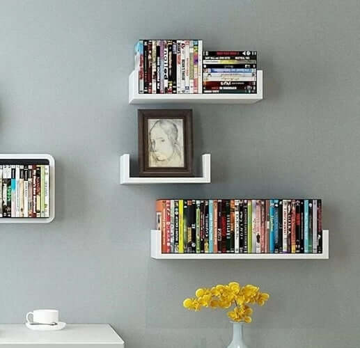 3-piece white wood wall-mounted shelf set displaying books and a picture frame on a gray wall.