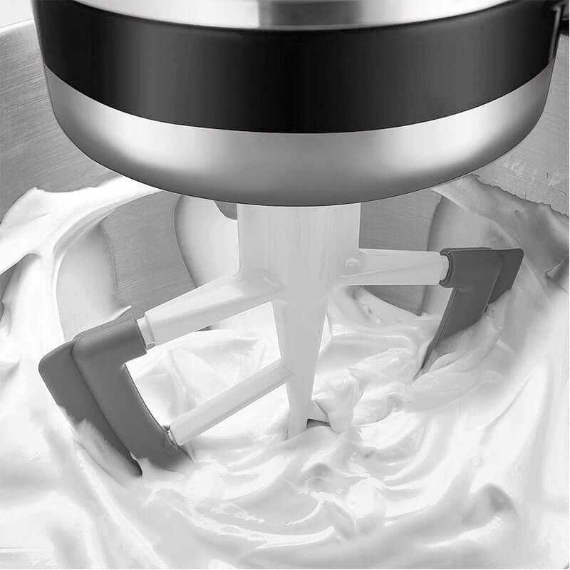 Kitchen machine mixing paddle accessories stirring a creamy mixture in a stainless steel bowl.