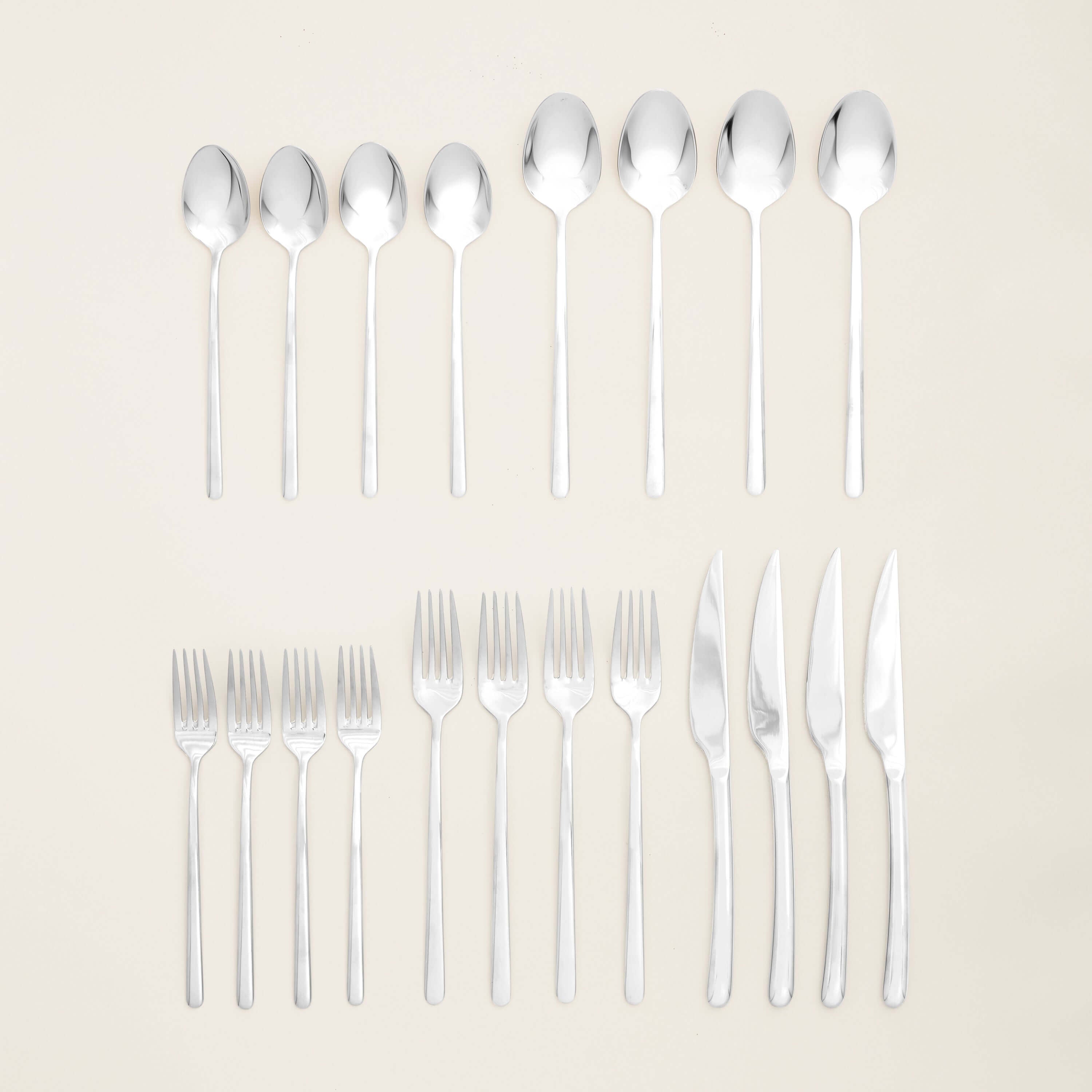 Emilia Mirror 20-Piece Flatware Set arranged on a neutral background, showcasing spoons, forks, and knives.