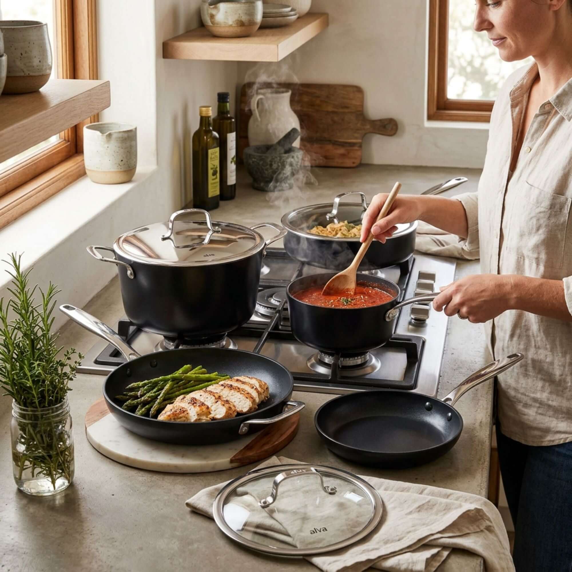 A person cooking on a stovetop using a Ceramic Nonstick 12-Piece Set with various pots and pans.