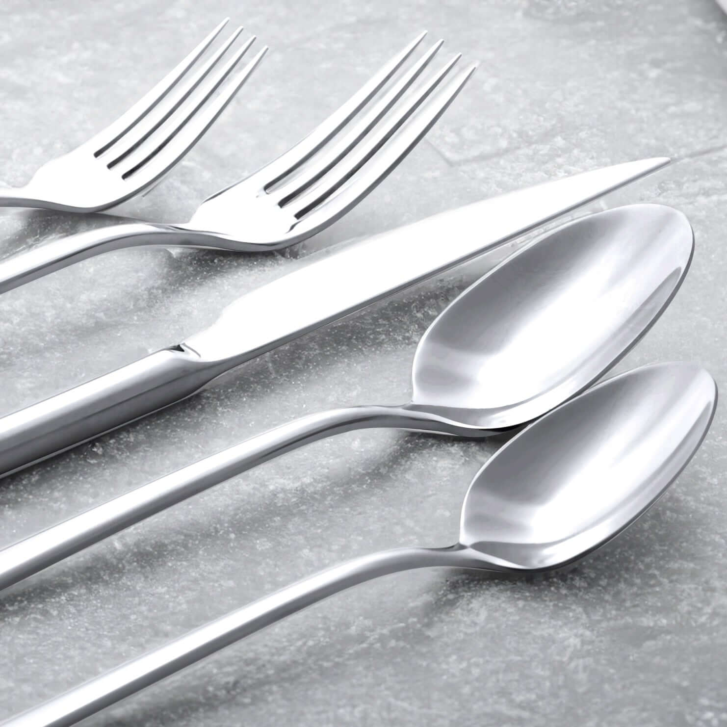 Emilia Mirror 20-Piece Flatware Set displayed with forks, knife, and spoons on a textured background.