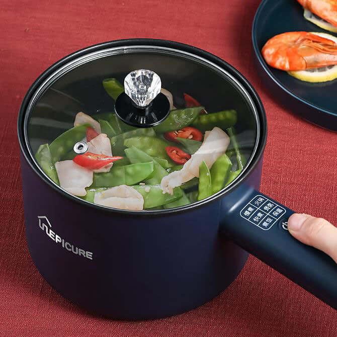 Electric cooker for dormitory cooking with vegetables steaming in a blue pot.