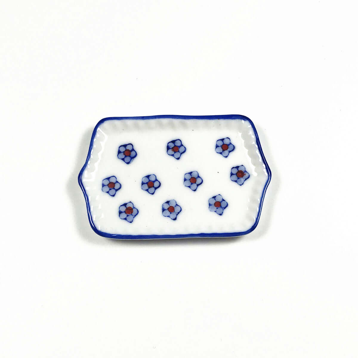 Miniature ceramic kitchen accessories featuring a floral design on a small plate in blue and white.