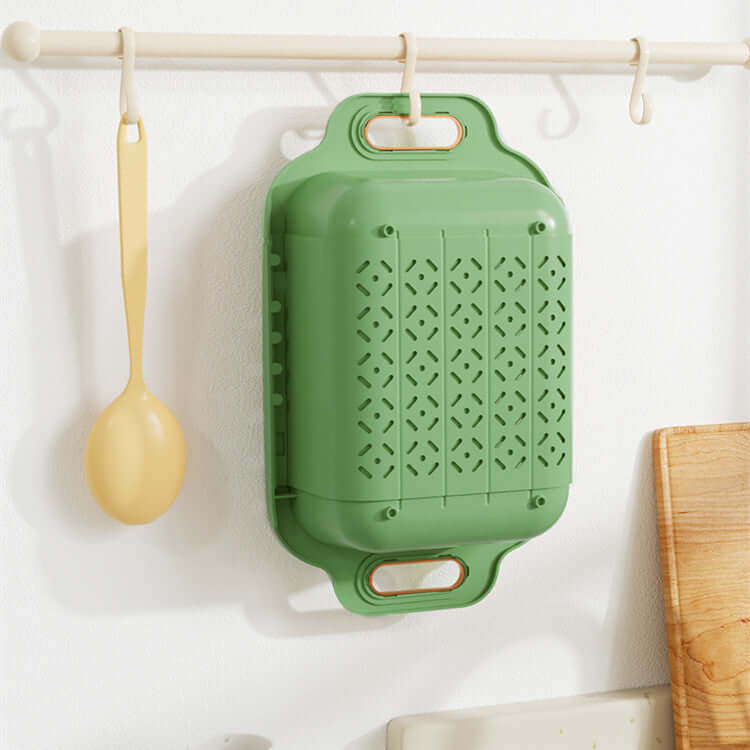 Home kitchen double retractable drainer basket in green color hanging on wall with a spoon.