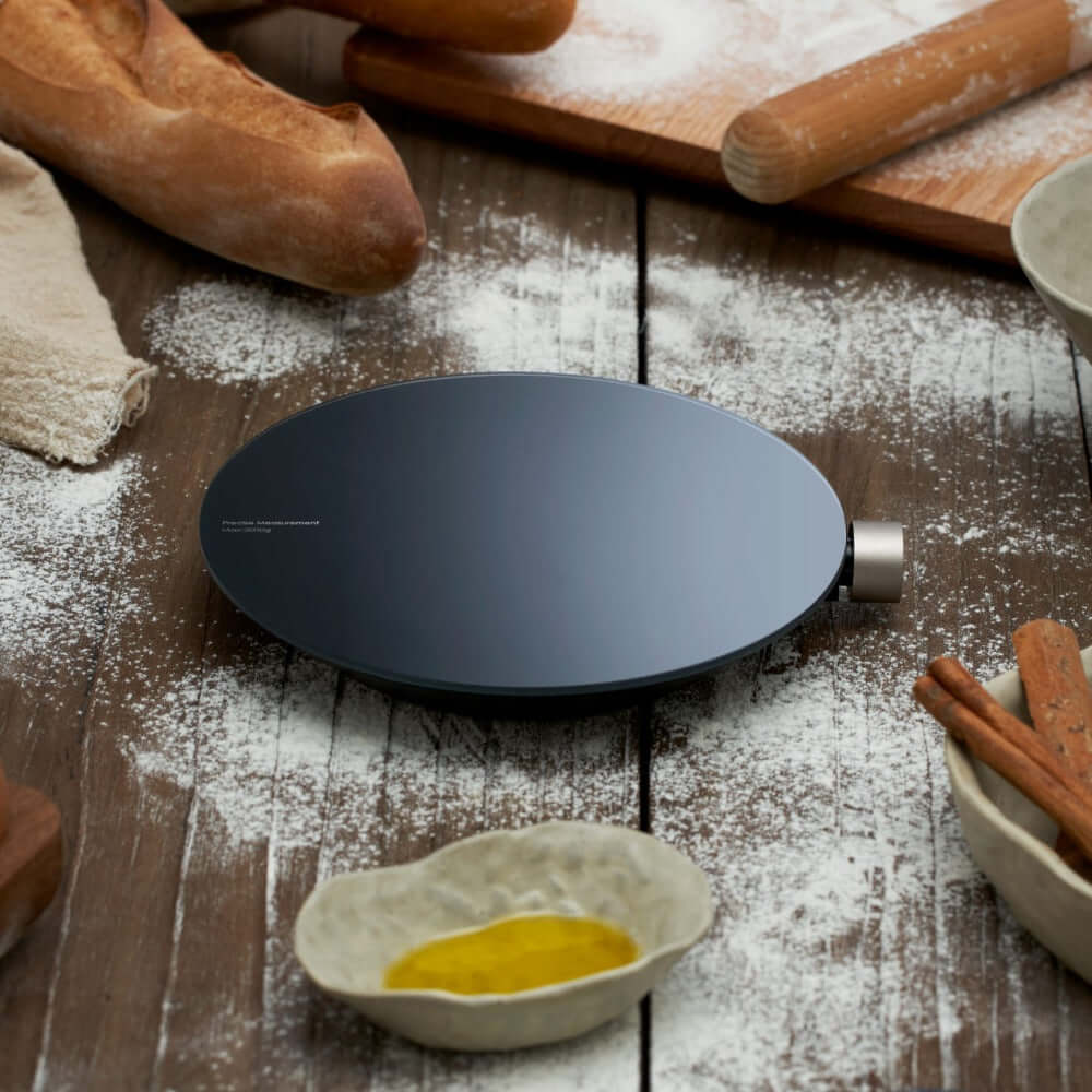 Smart Kitchen Scale on a rustic kitchen table with baking ingredients and flour scattered around.