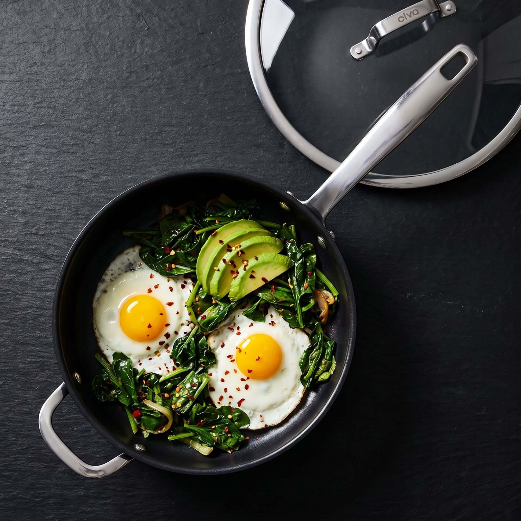 Ceramic Nonstick 12-Piece Set frying pan with eggs, spinach, and avocado on a dark background.