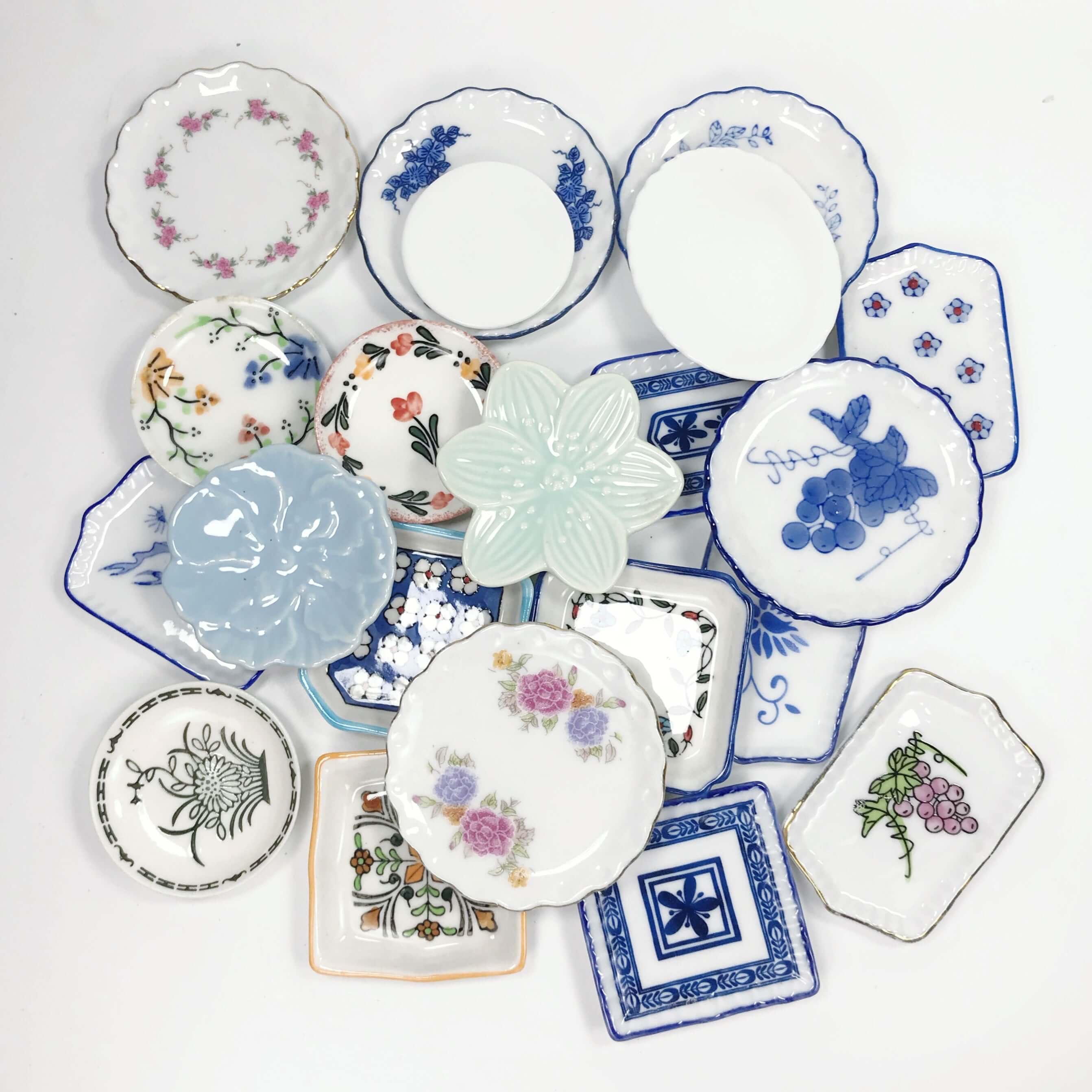 Miniature ceramic kitchen accessories featuring various ceramic plates in different shapes and designs.