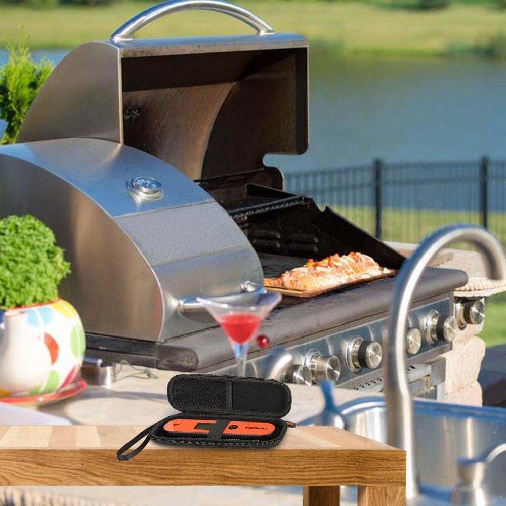 Digital BBQ Thermometer displayed next to a grill with meat cooking outdoors.