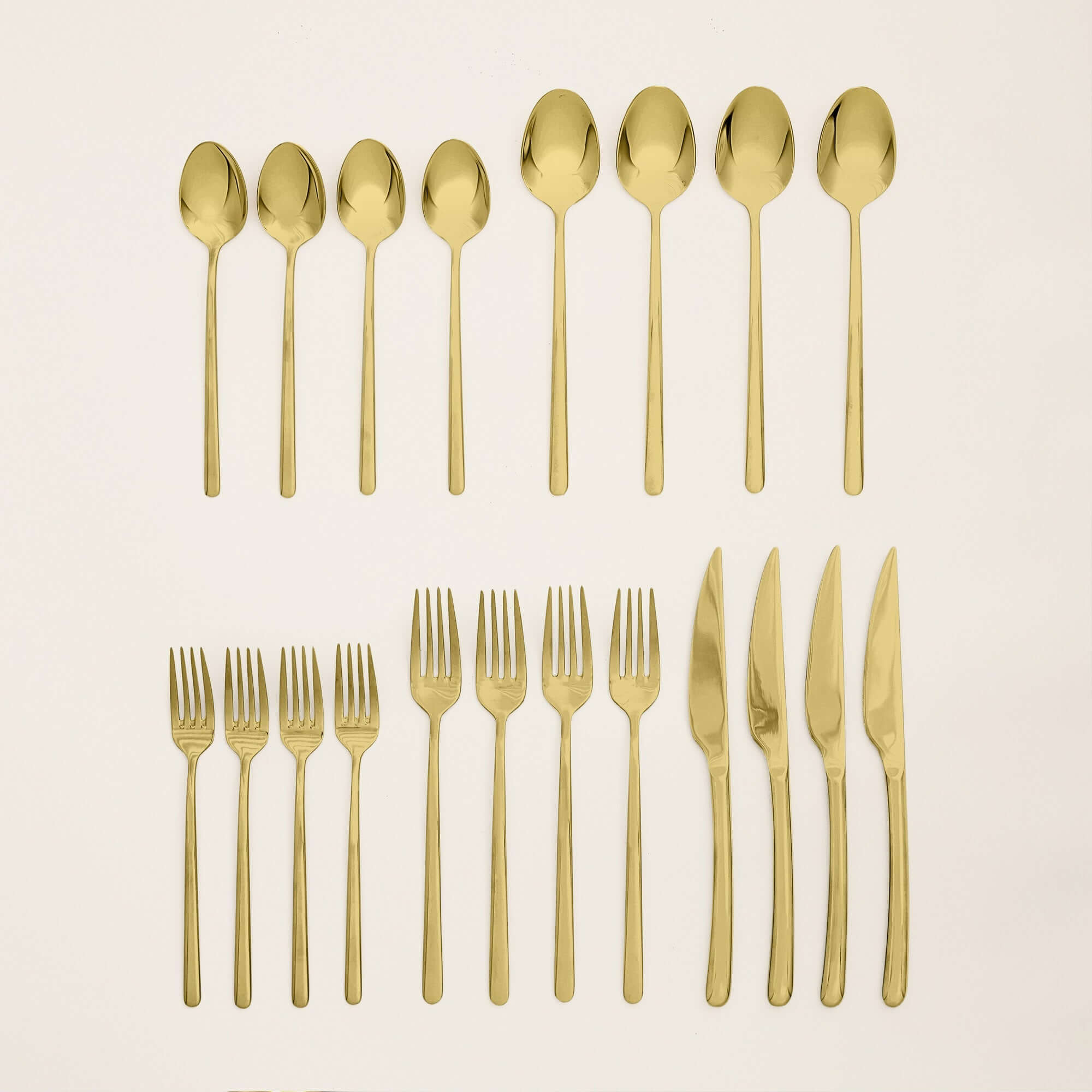 Emilia Mirror 20-Piece Flatware Set featuring gold-plated spoons, forks, and knives arranged beautifully.