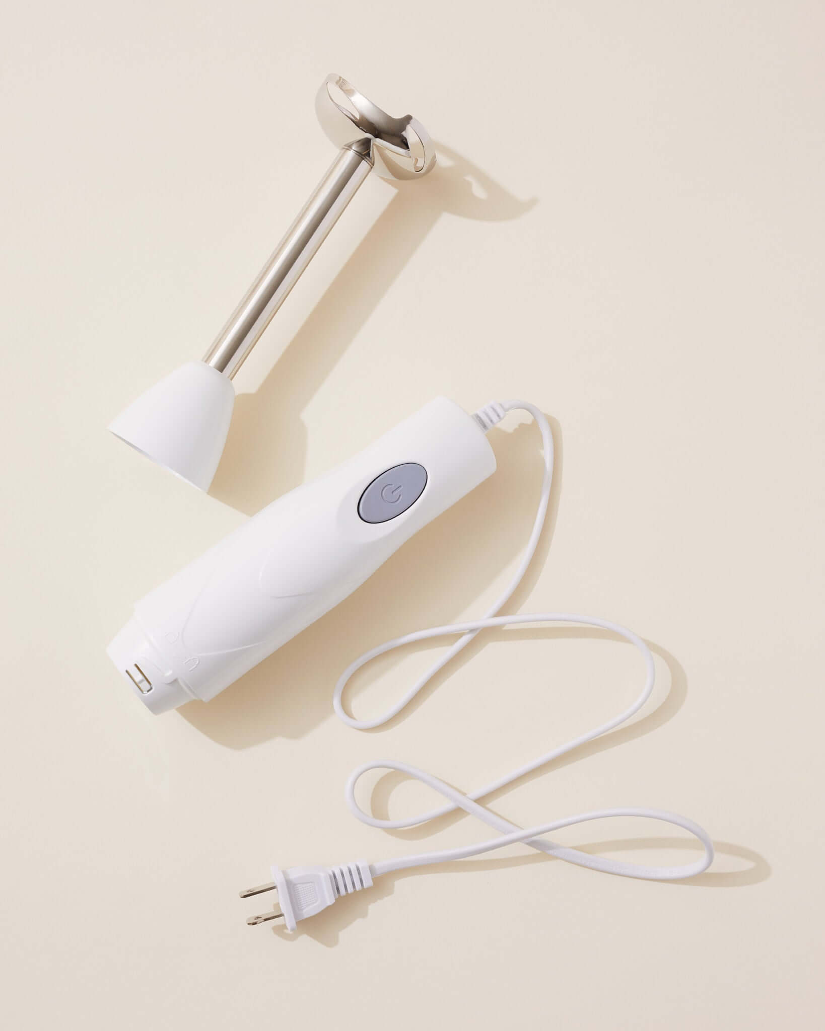 White Hand Held Blender with detachable blending shaft and power cord on a light background.